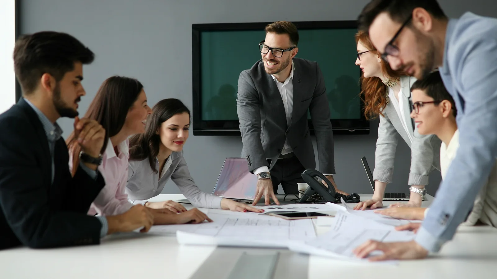 A diverse team of consultants collaborating around a laptop in a bright office